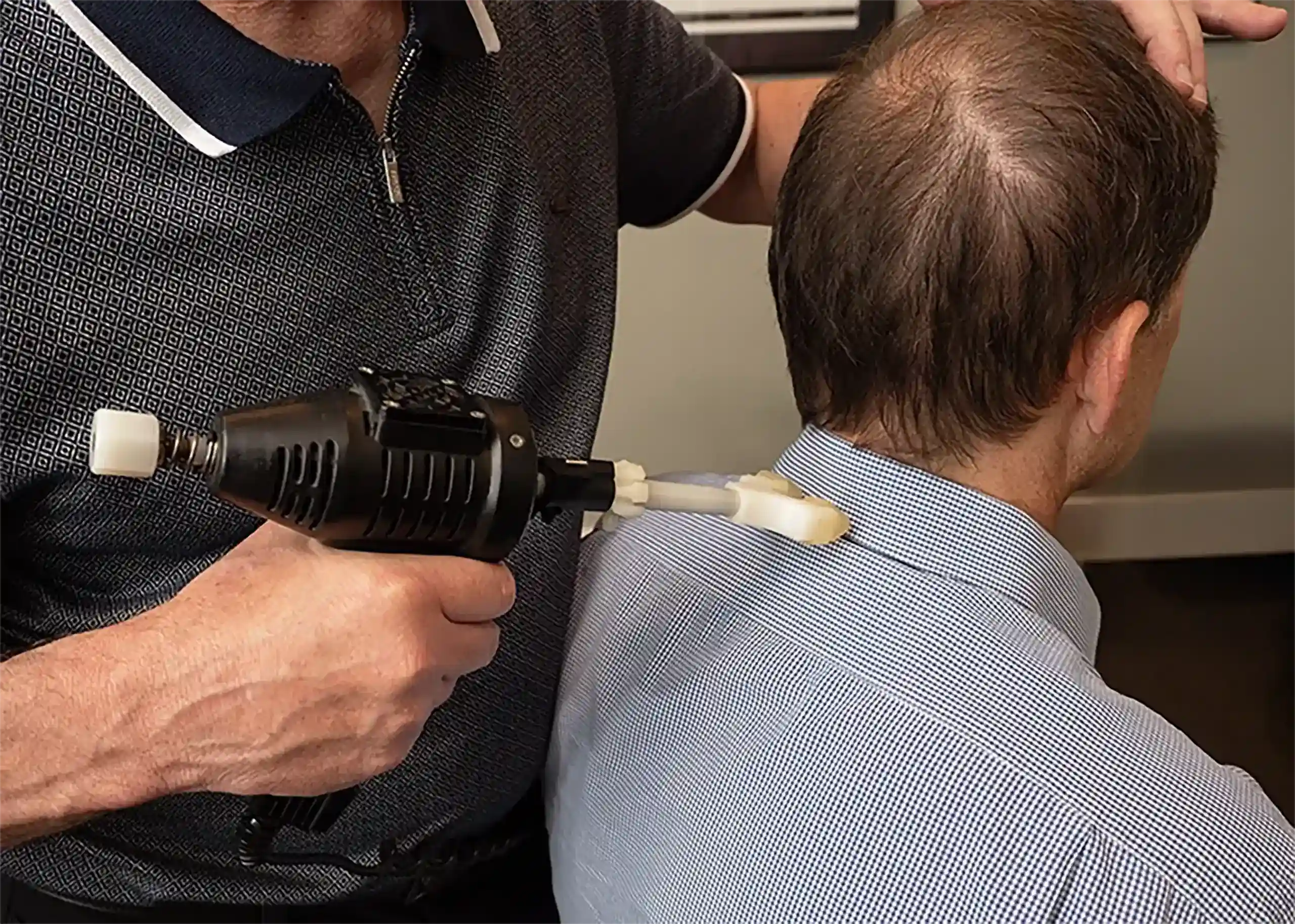 Dr. Crokin using an instrument-assisted adjustment technique on a patient's neck